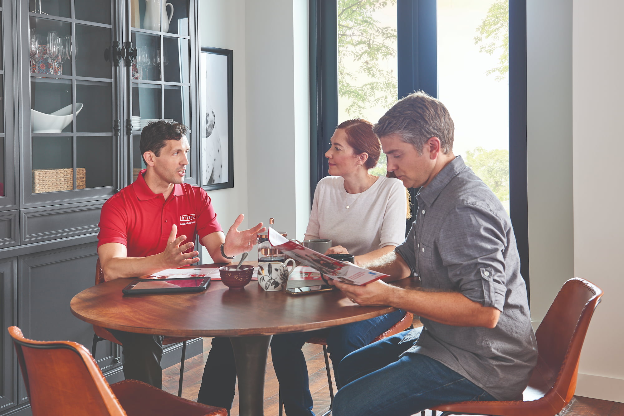 Bryant technician speaking with couple at kitchen table